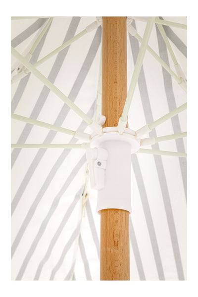 Nahaufnahme der zentralen Stange und der Stützspeichen eines gestreiften Sonnenschirms für den Außenbereich, von unten betrachtet.