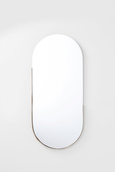 Ein gewölbter, rahmenloser Wandspiegel mit abgerundeter Oberseite und flacher Unterseite, der an einer schlichten weißen Wand angebracht ist.