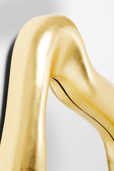 Nahaufnahme einer glänzenden, goldenen, geschwungenen abstrakten Spiegel vor einem schlichten weißen Hintergrund.