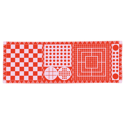 Ein rotes Badetuch  mit verschiedenen klassischen Brettspielmustern, darunter Schach, Dame und Tic-Tac-Toe.