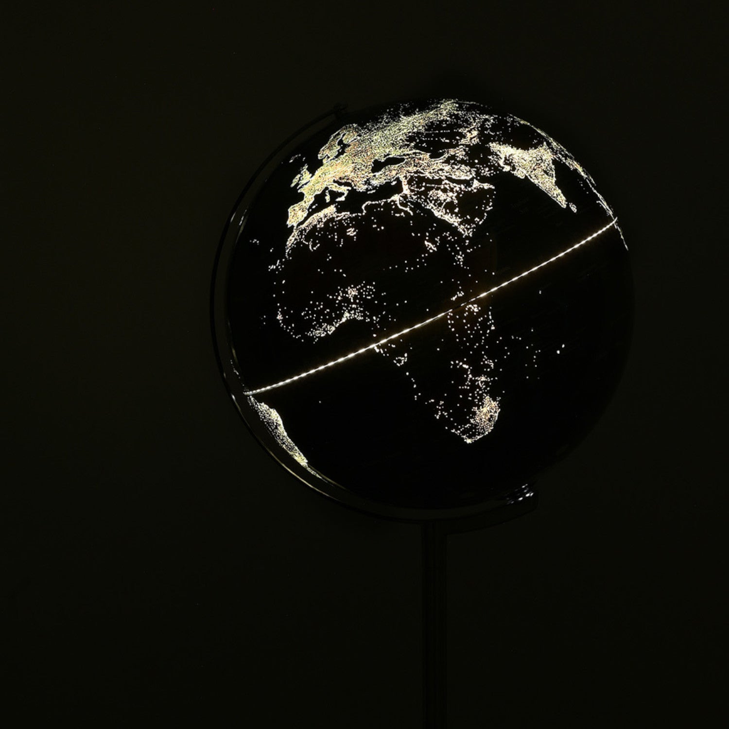 Ein dunkler Globus mit leuchtenden Stadtlichtern, die Europa, Afrika und Teile Asiens hervorheben.