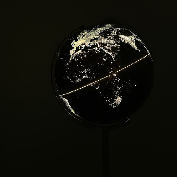 Ein dunkler Globus mit leuchtenden Stadtlichtern, die Europa, Afrika und Teile Asiens hervorheben.