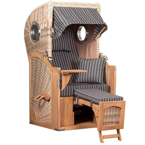 Ein Strandkorb mit Holzrahmen, gestreiften Kissen, einklappbaren Fußstützen, klappbaren Tischen und einem Baldachin, der für den Aufenthalt im Freien konzipiert ist.