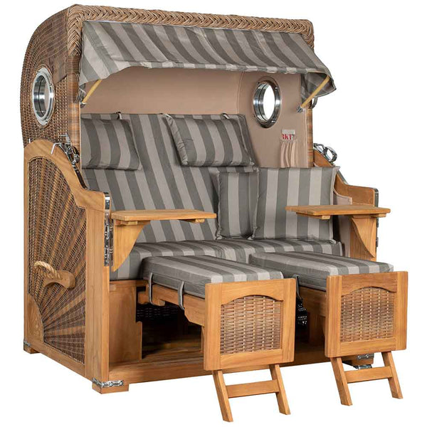 Ein Strandkorb aus Holz mit Baldachin, grau gestreiften Kissen, zwei ausziehbaren Fußstützen und klappbaren Seitentischen.