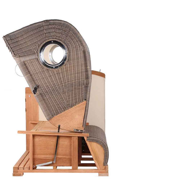 Seitenansicht eines Strandkorbs aus Holz und Korbgeflecht mit gebogener Rückenlehne und einem runden Fenster vor einem schlichten weißen Hintergrund.