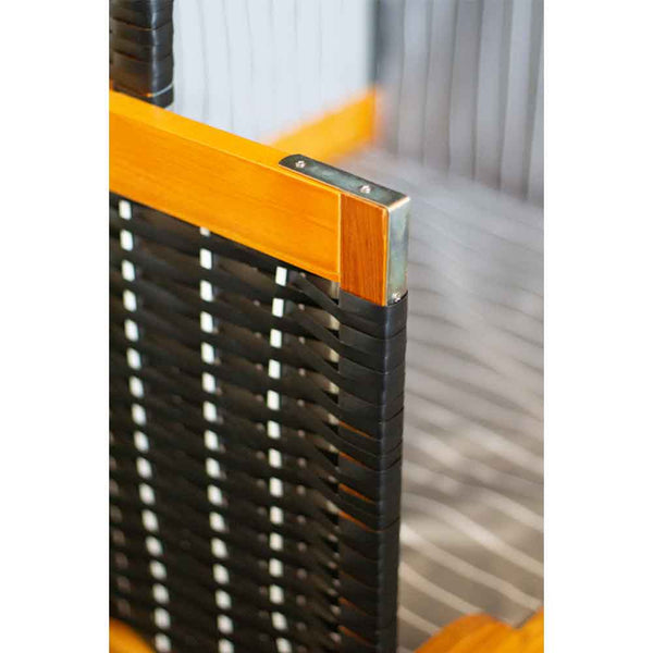 Nahaufnahme einer Stuhlarmlehne mit Holzrahmen mit Metalleckwinkel und schwarzen gewebten Bändern mit weißen Akzenten.