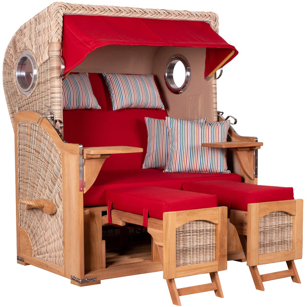 Ein Strandkorb mit rotem Sonnendach, zwei Sitzen, gestreiften Kissen, Klapptischen und Fußstützen.