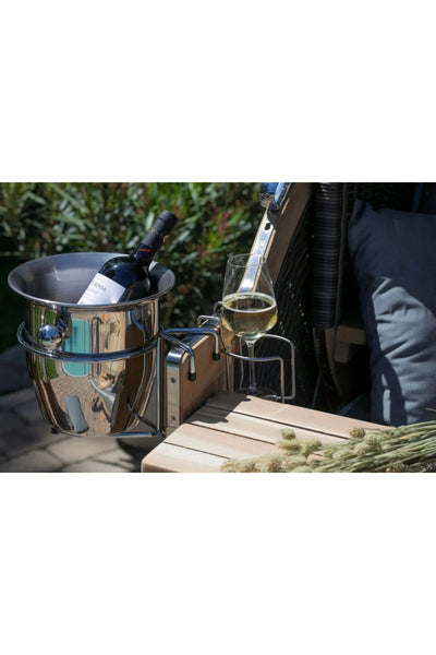 Ein Metalleimer mit einer Flasche, ein Glas Weißwein und ein Korkenzieher sind an der Seite eines Holzstuhls für den Außenbereich befestigt.