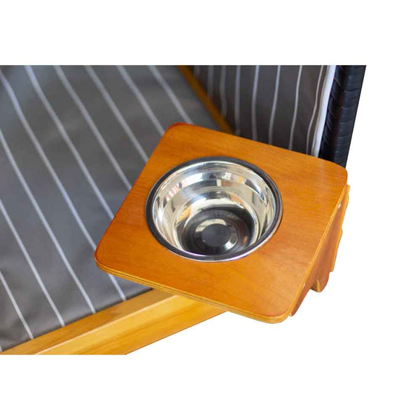 Ein Metallnapf wird in eine quadratische Holzhalterung eingesetzt, die an der Ecke eines gestreiften Stoffbetts oder Geheges befestigt ist.