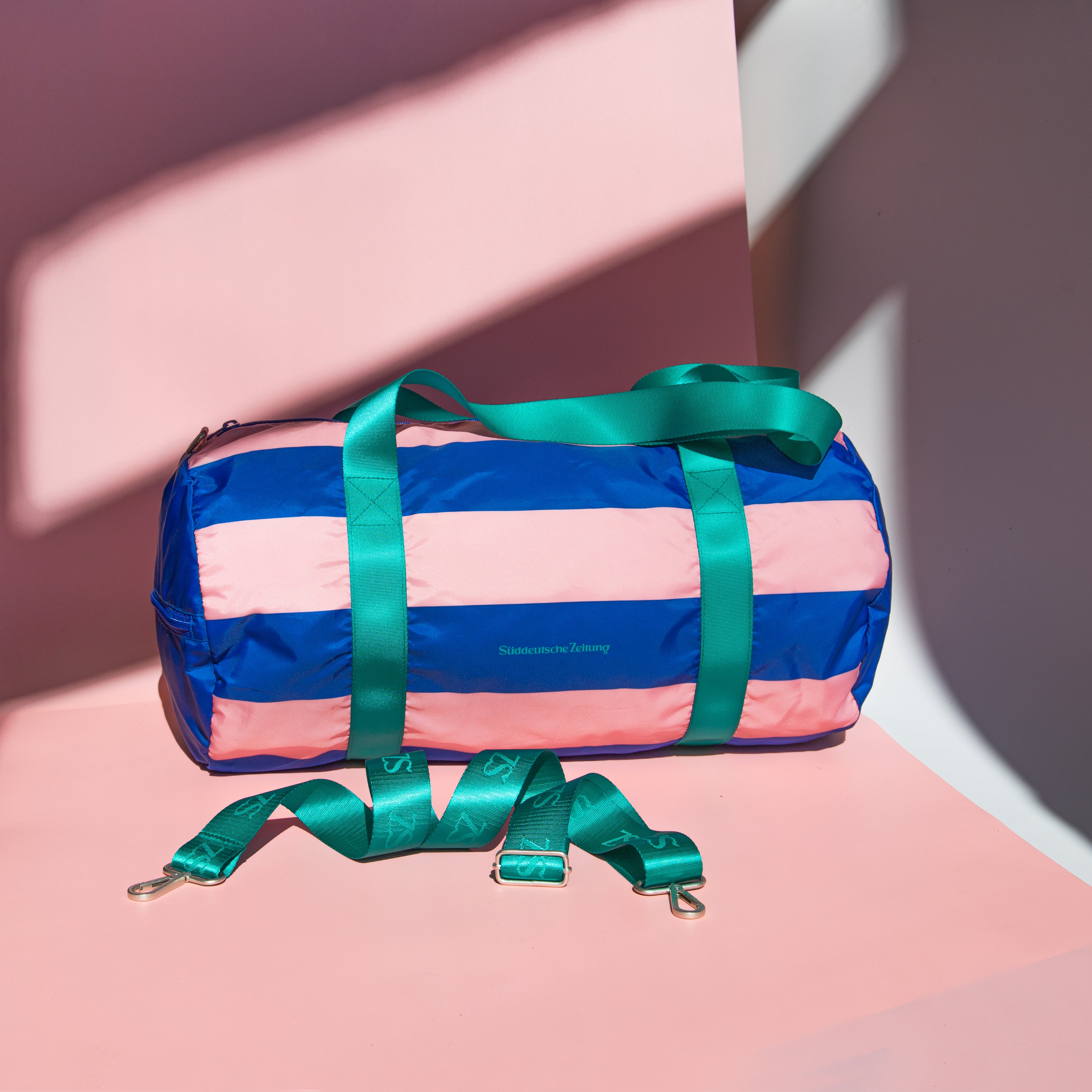 Tasche Weekender rosa blau gestreift  mit grünen Henkeln und Logo Süddeutsche Zeitung auf rosa Hintergrund 