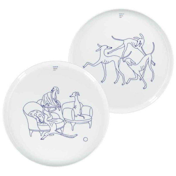 Zwei weiße Teller mit einfachen blauen Strichzeichnungen von Hunden, von denen einer auf einer Couch liegt und die anderen spielerisch miteinander umgehen.