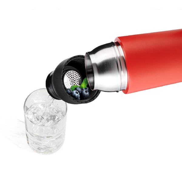 Eine rote Thermoskanne gießt Wasser durch ein Sieb mit Heidelbeeren und Minze in ein mit Eis gefülltes Glas.