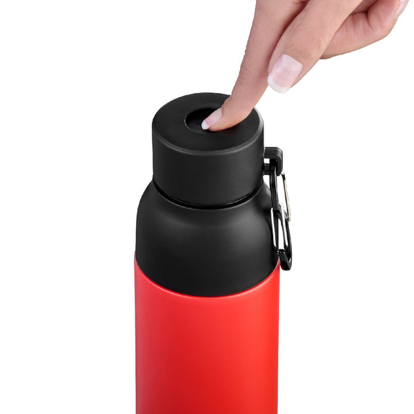Eine Hand drückt den Knopf auf dem schwarzen Deckel einer roten isolierten Wasserflasche, an der ein Karabiner befestigt ist.