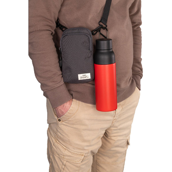 Die Person trug einen braunen Pullover und eine khakifarbene Cargohose, an der eine kleine schwarze Umhängetasche mit einer roten Wasserflasche befestigt war.