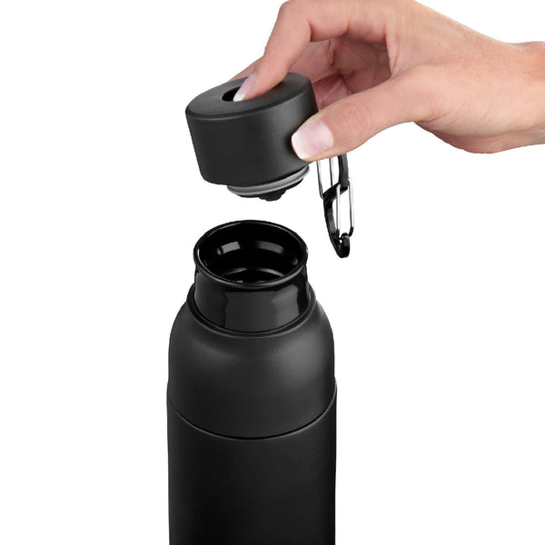 Eine Hand schraubt den Deckel von einer schwarzen Wasserflasche ab und gibt den Blick auf die offene Öffnung frei.