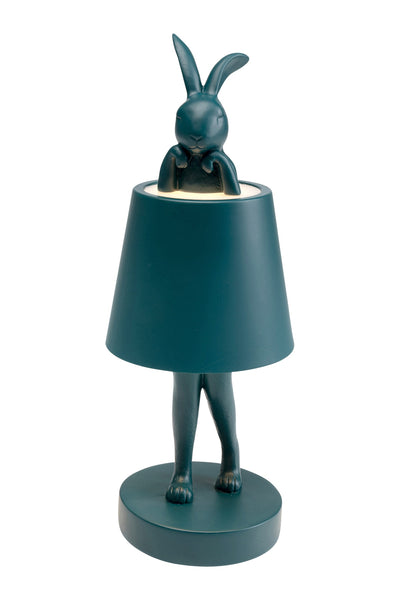 Tischlampe mit einer tealfarbenen Kaninchenfigur, deren Kopf und Oberkörper vom Lampenschirm bedeckt sind, so dass die Ohren und Unterschenkel sichtbar bleiben.