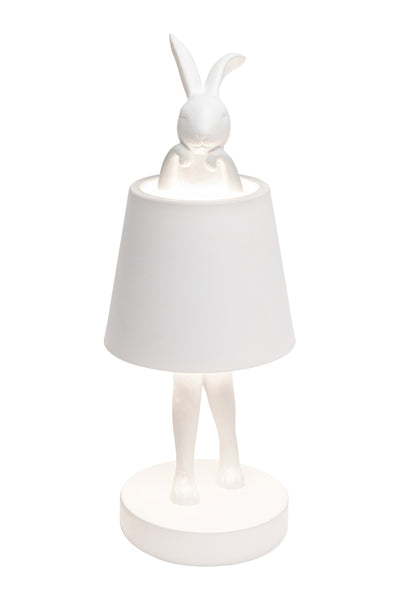 Weiße Tischlampe mit einer Hasenfigur, bei der der Lampenschirm den Oberkörper bedeckt und Kopf und Beine des Hasen sichtbar sind.