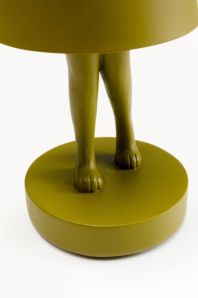 Nahaufnahme einer Lampe mit einem Sockel, der wie Hundebeine und -pfoten aussieht, alles in einer soliden olivgrünen Farbe.