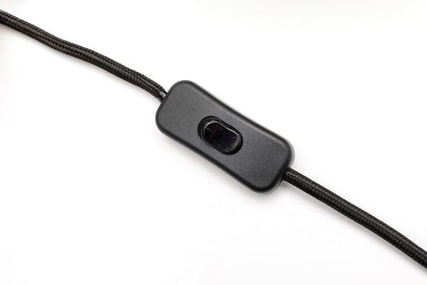 Nahaufnahme eines schwarzen Inline-Schalters, der an einem geflochtenen Stromkabel auf weißem Hintergrund befestigt ist.
