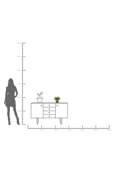 Eine maßstabsgetreue Abbildung zeigt ein Sideboard mit einer Topfpflanze und einer kleinen Lampe darauf, daneben die Silhouette einer Person zum Größenvergleich.