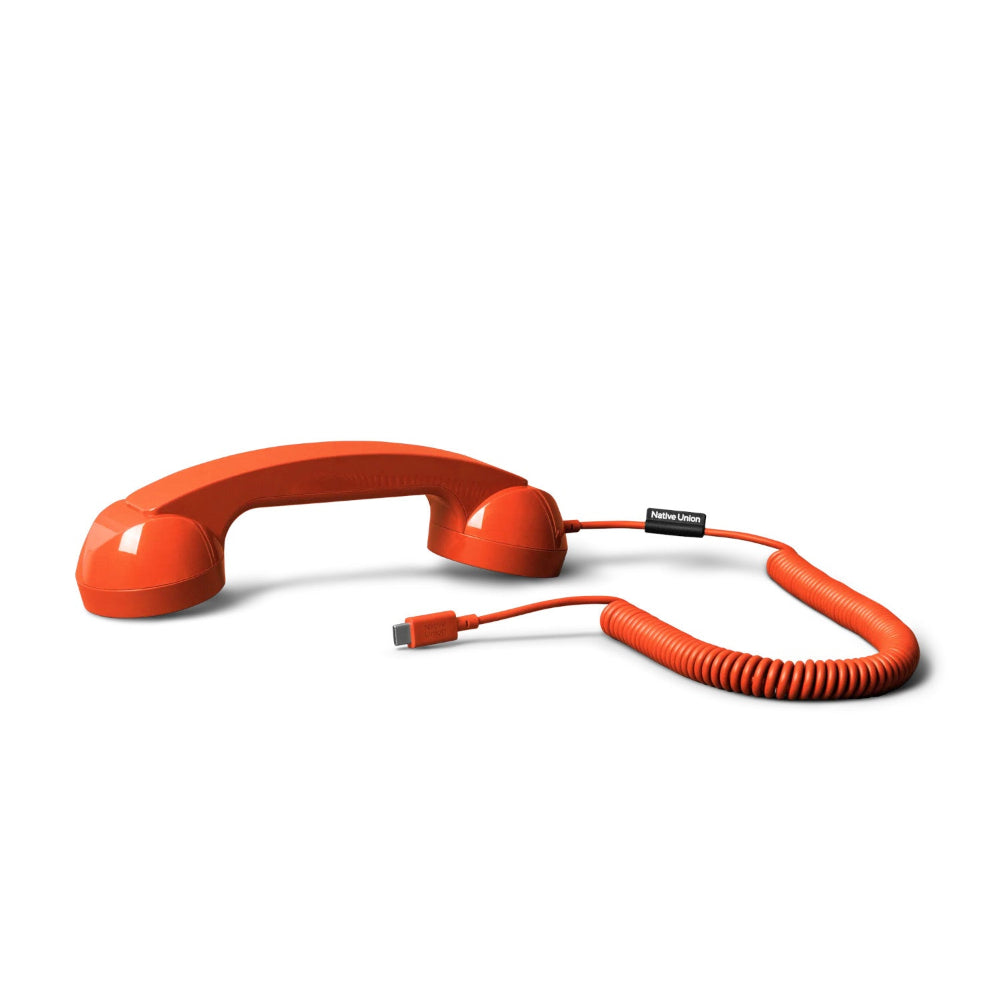 Ein roter Telefonhörer im Retro-Stil mit einem Spiralkabel, das in einem USB-Anschluss endet, mit der Aufschrift Native Union auf weißem Hintergrund.