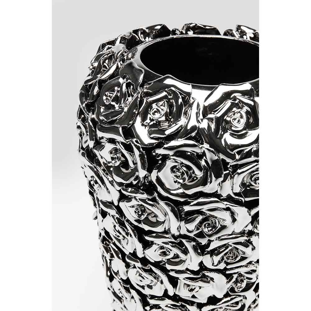 Nahaufnahme einer glänzenden silbernen Vase mit erhabenen Rosenmustern vor einem schlichten Hintergrund.