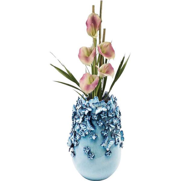 Blaue Vase mit dekorativen Blumen, die rosa Calla-Lilien und grüne Blätter enthält.