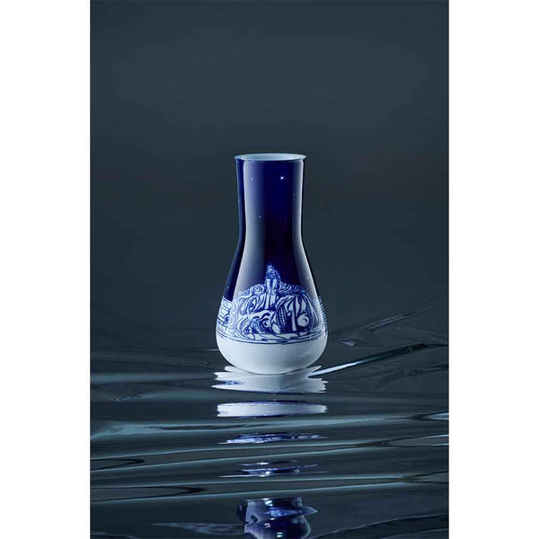 Eine blau-weiße Keramikvase mit einem verschlungenen Muster steht auf einer spiegelnden Oberfläche vor einem dunklen Hintergrund.