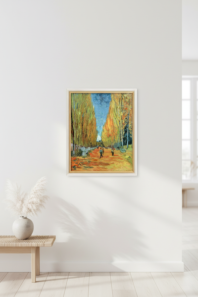 Ein gerahmtes Bild eines von Bäumen gesäumten Weges hängt an einer weißen Wand über einer Holzbank mit einer Vase mit Pampasgras in einem hellen, minimalistischen Raum.