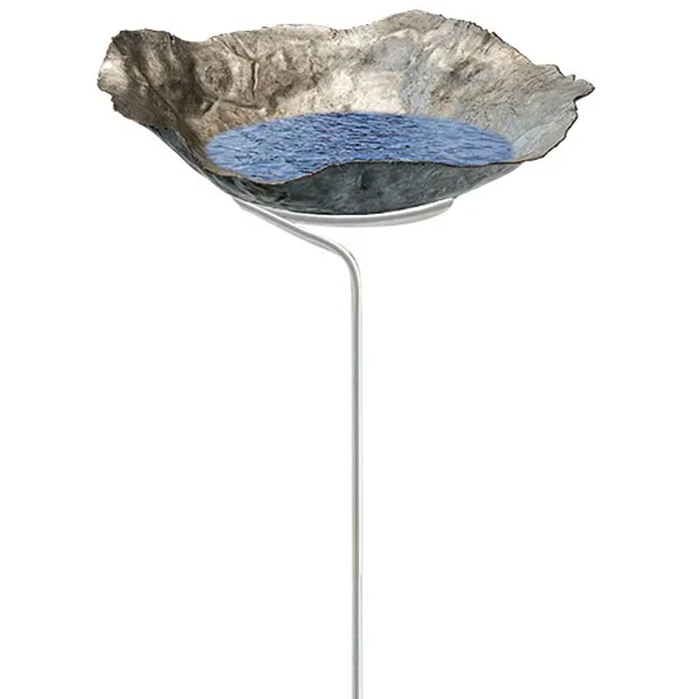 Das Vogelbad/Gartenstecker „Lotus“ ist ein Vogelbad aus Metall mit einem strukturierten, felsigen Becken, das teilweise mit Wasser gefüllt ist und auf einem schlanken weißen Ständer steht.