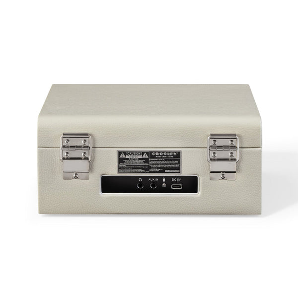 Geschlossenes, beigefarbenes Crosley-Plattenspielergehäuse mit silbernen Metallverschlüssen und elektronischen Eingangs-/Ausgangsanschlüssen auf der Vorderseite.