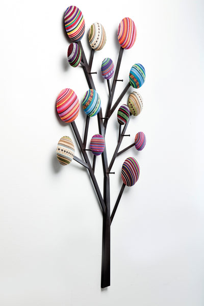Wandbild eines Baumes mit schwarzen Metallzweigen und bunten, runden, gestreiften Stoffkreisen als Blätter.