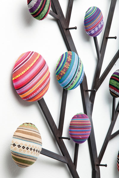 Die Metallbaum-Wandkunst besteht aus runden, gepolsterten Formen, die mit bunten, gestreiften Textilmustern überzogen sind.