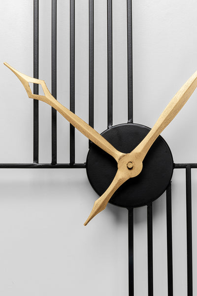 Goldene Zeiger auf einer modernen Wanduhr aus schwarzem Metall mit minimalistischem geometrischem Design.