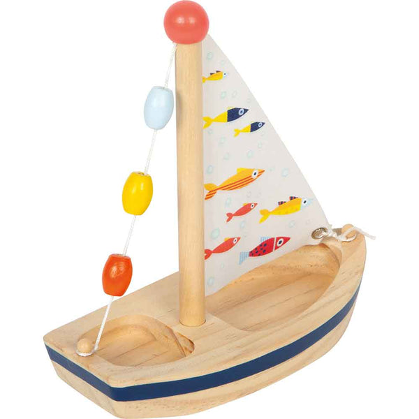 Ein Spielzeug-Segelboot aus Holz mit einem gestreiften Rumpf, bunten Perlen am Mast und einem Segel, das mit Abbildungen von Fischen verziert ist.
