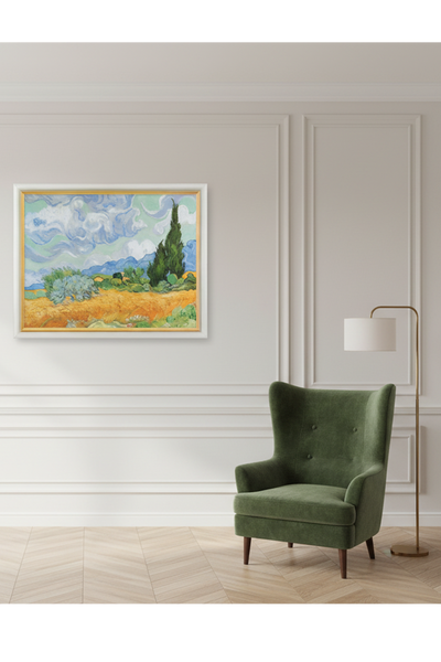 Ein gerahmtes Gemälde eines Weizenfeldes, Zypressen und wirbelnder Wolken unter einem blauen Himmel in einem Wohnraum mit grünem Sessel und Stehlampe. 