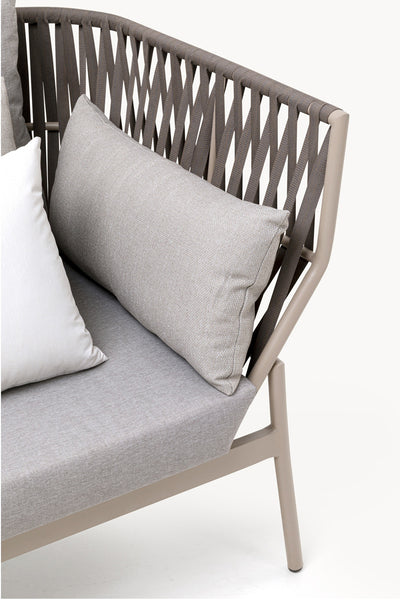 Nahaufnahme eines modernen Outdoor-Stuhls mit einem hellgrauen Kissen, zwei Kissen und einer geflochtenen Seilrückenlehne auf einem Metallrahmen.