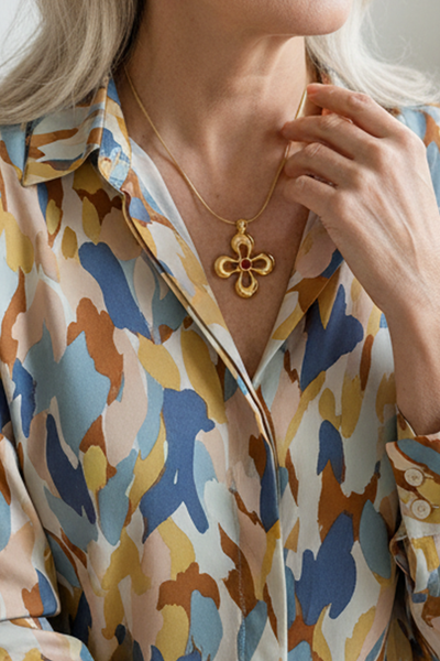 Das Bild zeigt eine Dame, die das Collier mit einem Anhänger in Form einer Blume und einem heilbringendem Granat als Glücksstein in der Mitte um den Hals trägt. 