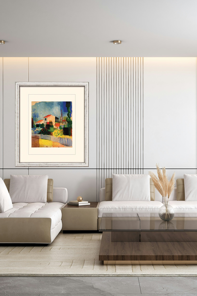 Gerahmtes abstraktes Gemälde eines Hauses mit rotem Dach, umgeben von Grün und einem Garten, unter blauem Himmel, auf weißem Hintergrund in einem modernen Wohnzimmer an der Wand hängend. 