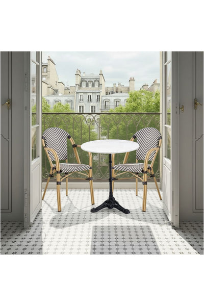 Ein kleiner Balkon mit einem runden Tisch und zwei Stühlen blickt durch offene Flügeltüren auf die klassischen Dächer der Stadt.