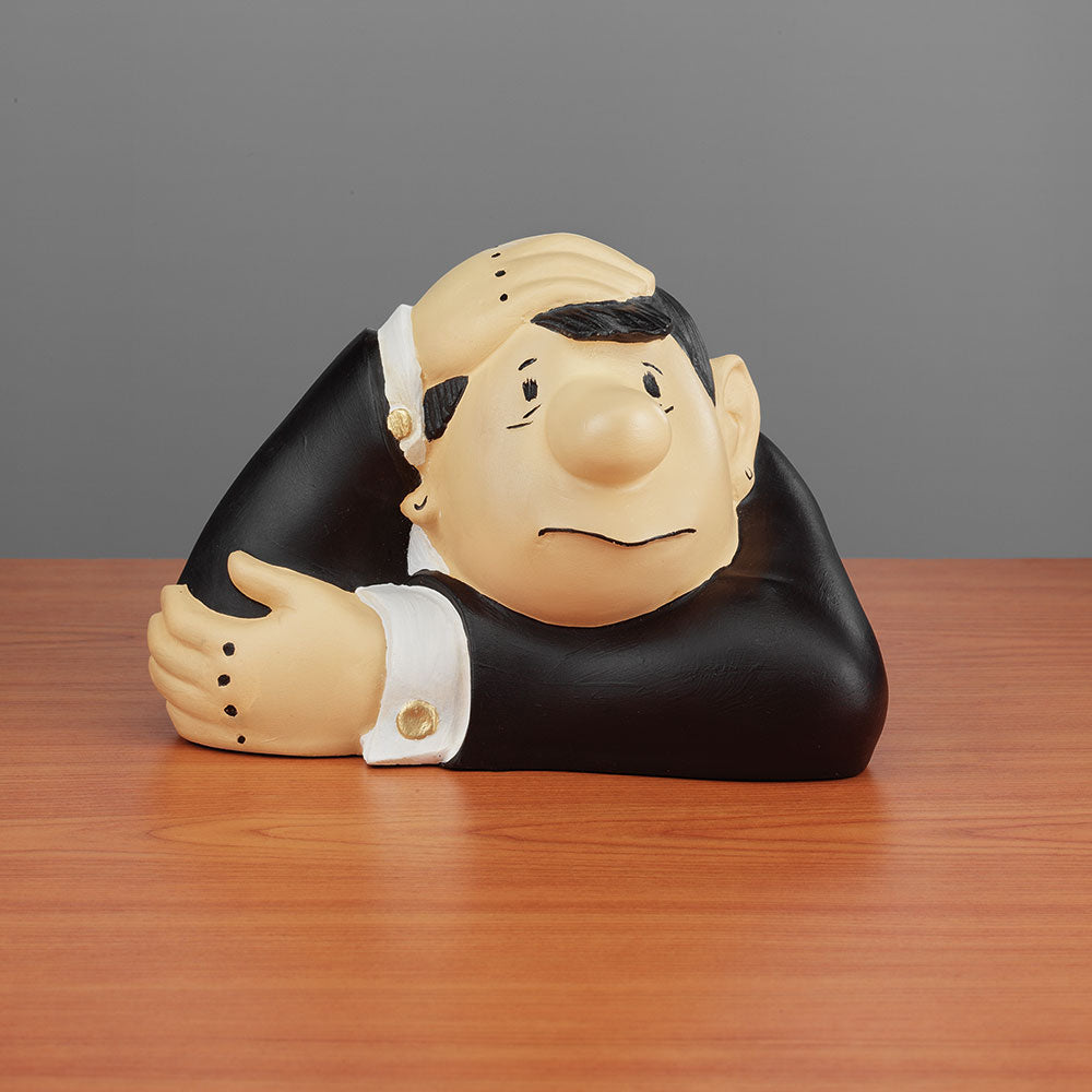 Cartoonartige Figur eines besorgten Mannes, der seinen Kopf auf eine Hand stützt und an einem Holztisch sitzt.