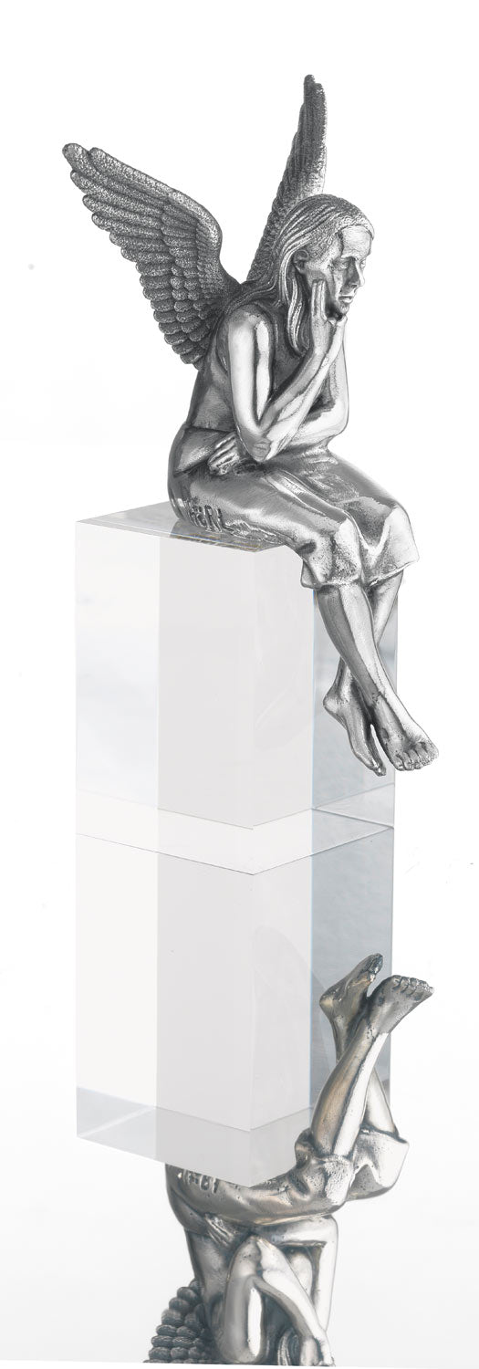 Die silberne Engelsstatue sitzt nachdenklich auf einem durchsichtigen Würfel, darunter ist ihr Spiegelbild sichtbar.