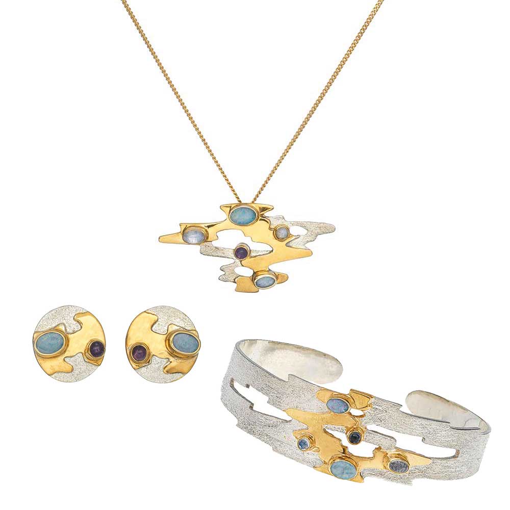 Ein Schmuckset mit silbernen und goldenen Ohrringen, einer passenden Halskette mit Anhänger und einem Armband mit blauen Steinen.