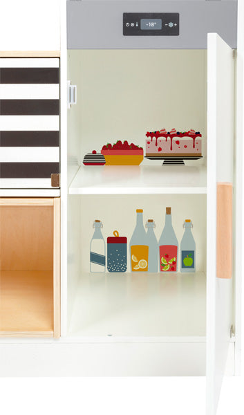 Die Kinderküche modular XL ist ein Spielzeugkühlschrank mit zwei Ablagen, auf denen Kuchen, Beeren und Getränke abgebildet sind, dargestellt mit geöffneter Tür.