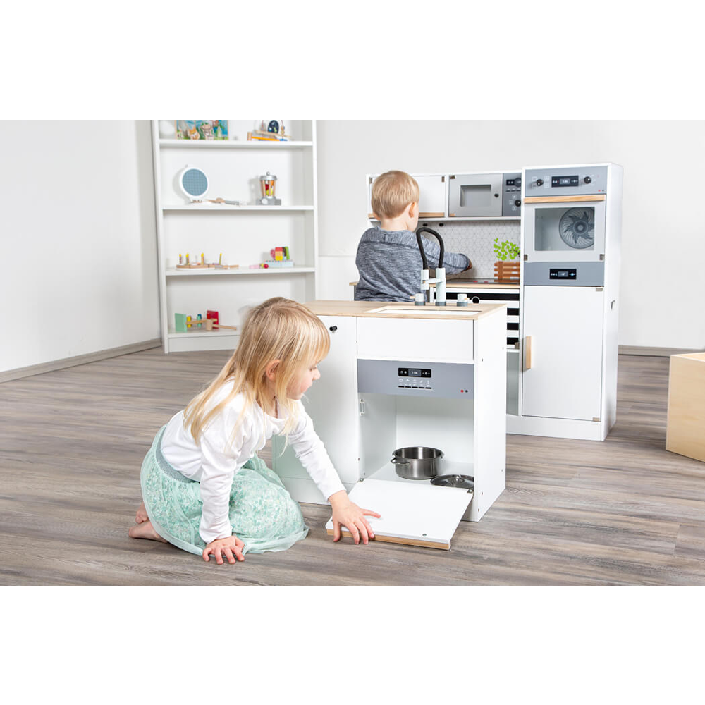 Zwei Kinder spielen mit der Kinderküche modular XL, einem weißen Spielzeugküchenset, in einem hellen, modernen Raum mit Holzboden.