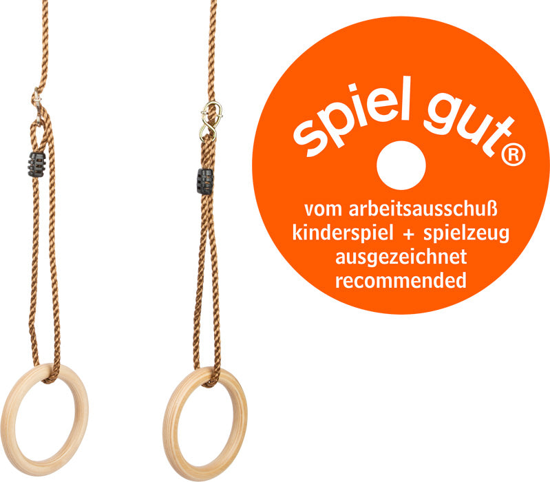 Neben einem orangefarbenen „spiel gut“-Spielzeug-Empfehlungsschild hängen an Seilen zwei Turnringe Holz aus Holz.