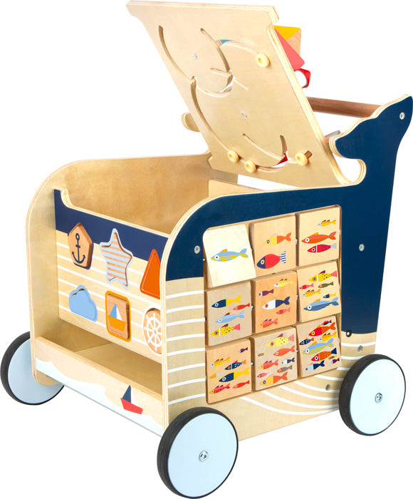 Der Lauflernwagen Wal ist ein Spielzeugkarren aus Holz mit Rädern, bunten Fischblöcken, einem Formsortierer und Dekorationen im nautischen Stil.