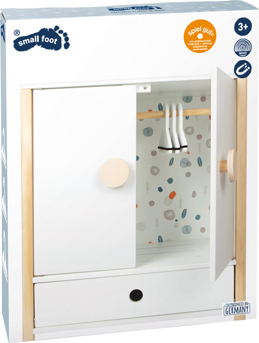 Puppenschrank „Little Button“: weißer Spielzeugkleiderschrank mit hängender Kleidung, Schiebetür und unterer Schublade, in Markenverpackung.