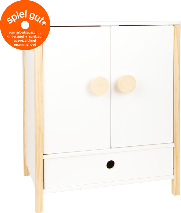 Der Puppenschrank „Little Button“ ist ein weißer Spielzeugschrank aus Holz mit zwei Türen mit runden Knöpfen, einer unteren Schublade und einem orangefarbenen Spiel Gut-Etikett.