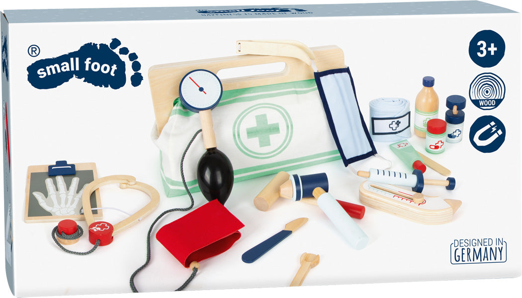 Die Arzttasche ist ein Spielzeug-Arztkoffer mit medizinischen Instrumenten aus Holz, Tasche, Stethoskop, Spritze und Flaschen in einer weißen Box, geeignet für Kinder ab 3 Jahren.